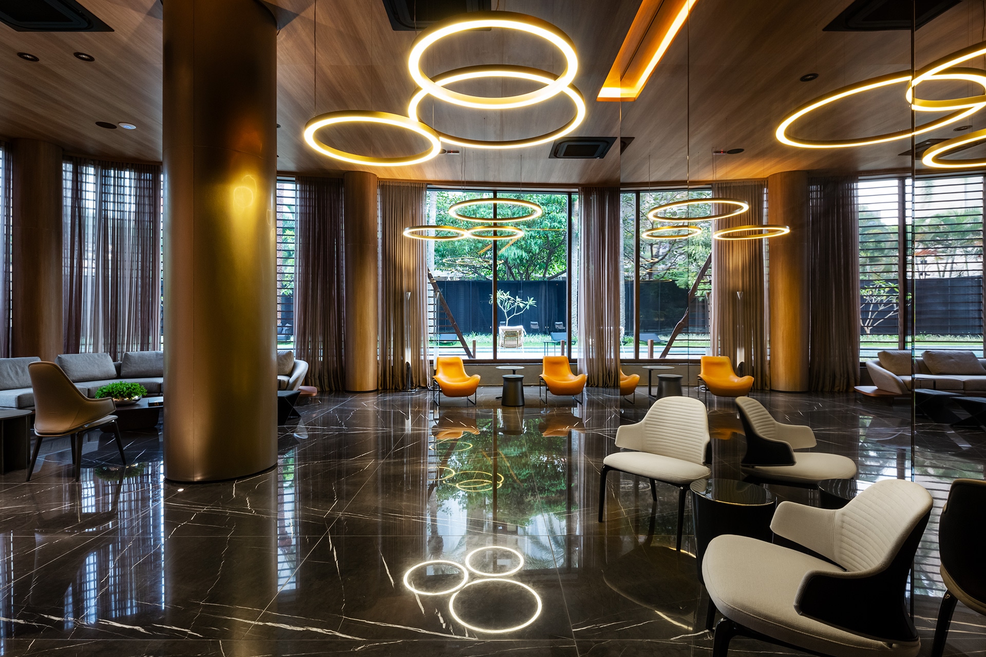 Lounge com anéis de luz, poltronas e piso de mármore
